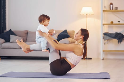 Focused at yoga exercises. Mother with her little daughter is at home together.