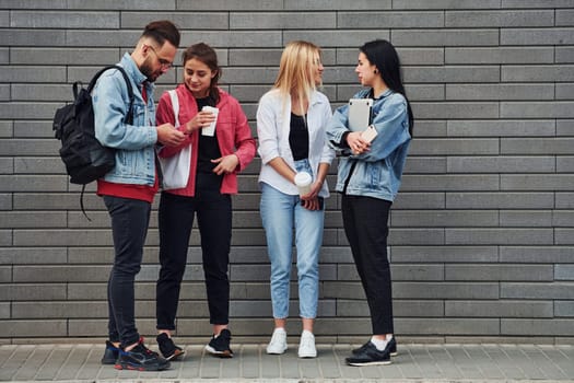 Three women and one guy is outdoors near building at daytime.