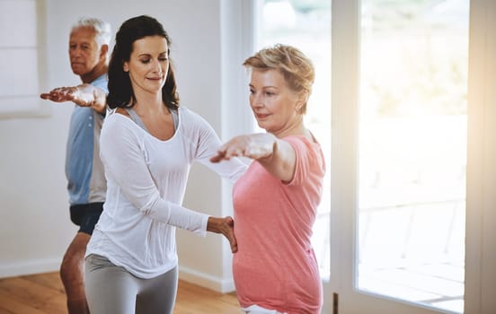 Living a healthy lifestyle through yoga. a teacher helping a senior woman during a yoga class