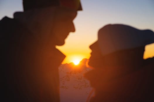 Couple portrait, silhouette of lovers looking at each other and smiling, against the backdrop of the setting sun.