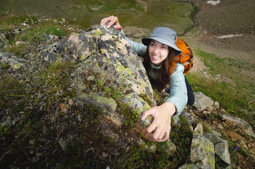 In summer, a young woman goes rock climbing while hiking in the mountains. Female rock climber on the mountain.