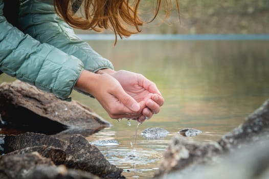 Close up, hands in the water from a glacial stream from the spring thaw. Clean refreshing drinking water in the forest. Pure water natural resources concept.