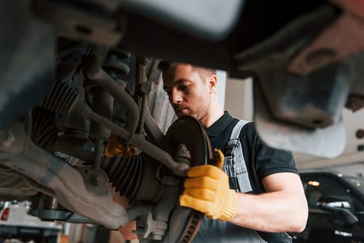 Professional service. Man in uniform is working in the auto service.