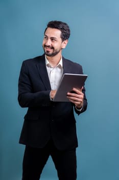 Confident businessman in formal suit holding tablet with surprise look for promotion or advertising. Facial expression and gestures indicate excitement and amazement on an isolated background. Fervent