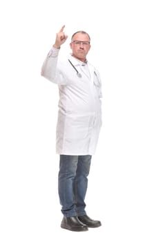 Cheerful mature doctor looking at camera and pointing away while standing against white background