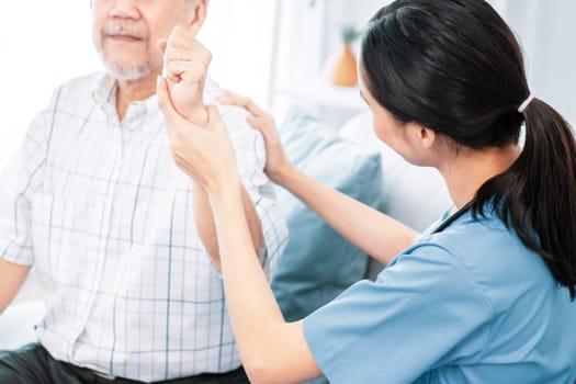 Caring young female doctor performing osteopathy treatment for a contented senior patient. At-home medical treatment for an Asian senior patient, joint pain treatment, medical service for seniors.