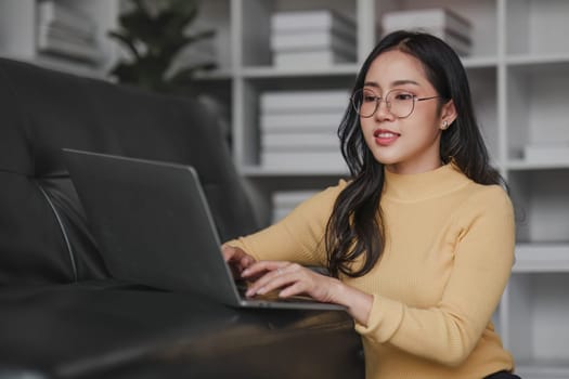 Happy young Asian business woman successful excited raised hand rejoicing with laptop at home...