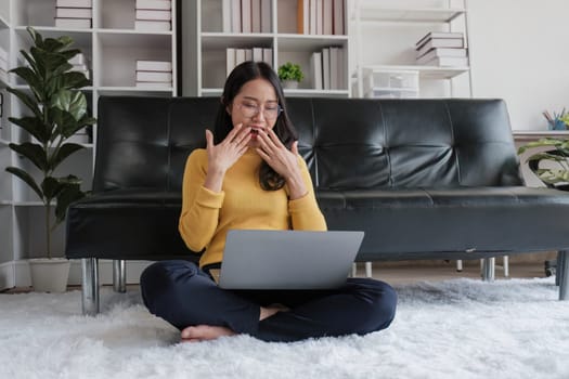 Happy young Asian business woman successful excited raised hand rejoicing with laptop at home...