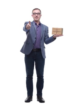 Cheerful handsome well-dressed young man in glasses holding gift box and looking at camera with smile while standing against white background