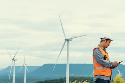 Engineer working on a wind farm atop a hill or mountain in the rural. Progressive ideal for the future production of renewable, sustainable energy. Energy generation from wind turbine.