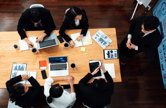 Top view manager or office worker give presentation in harmony conference room to business colleague, BI data dashboard on screen and pile of financial analyzed data reports on meeting table.