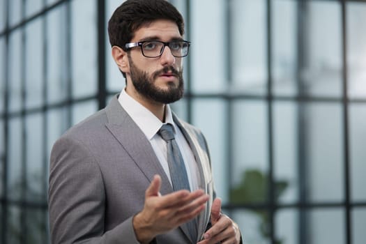 Portrait of serious handsome successful businessman in glasses and suit.