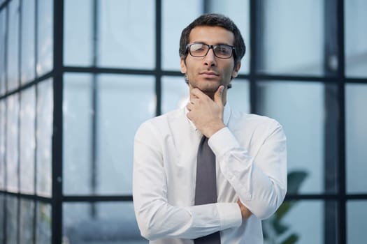 Thinking about business. Thoughtful young man in formalwear looking at camera while holding hand on chin
