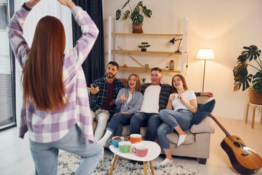 Playing game with using body language and poses. Group of friends have party indoors together.