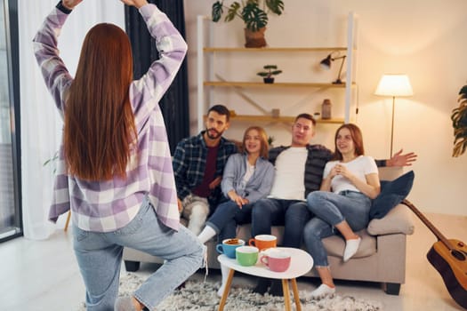 Playing game with using body language and poses. Group of friends have party indoors together.
