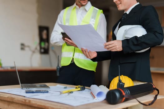 multi ethnic engineer brainstorming and measuring for cost estimating on blueprint and floor plan drawings about design architectural and engineering for houses and buildings.