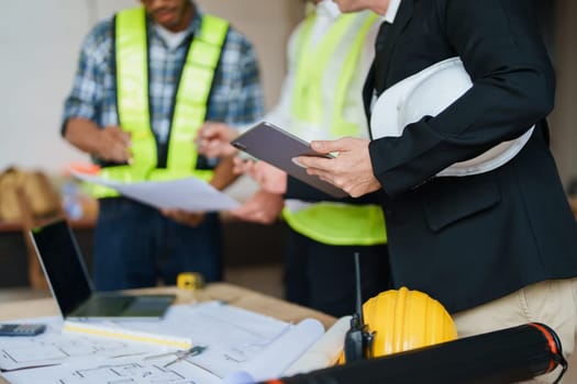 multi ethnic engineer brainstorming and measuring for cost estimating on paperworks and floor plan drawings about design architectural and engineering for houses and buildings.