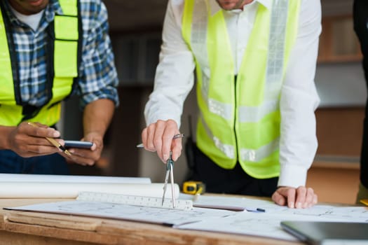 multi ethnic engineer brainstorming and measuring for cost estimating on paperworks and floor plan drawings about design architectural and engineering for houses and buildings.