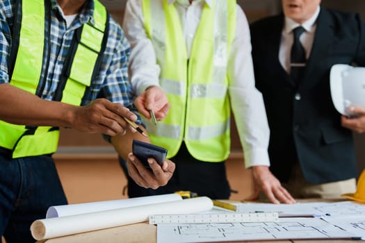 multi ethnic engineer brainstorming and measuring for cost estimating on paperworks and floor plan drawings about design architectural and engineering for houses and buildings.