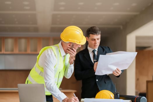 multi ethnic engineer brainstorming and measuring for cost estimating on blueprint and floor plan drawings about design architectural and engineering for houses and buildings.