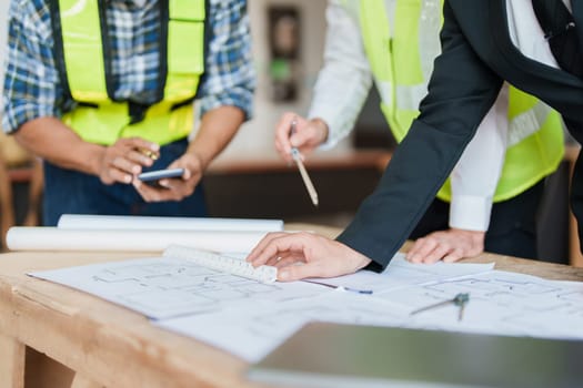 multi ethnic engineer brainstorming and measuring for cost estimating on paperworks and floor plan drawings about design architectural and engineering for houses and buildings.