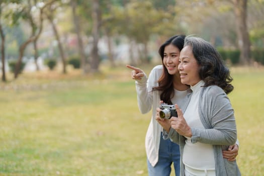 Asian teenage mother and daughter walking in park with camera to capture memories.