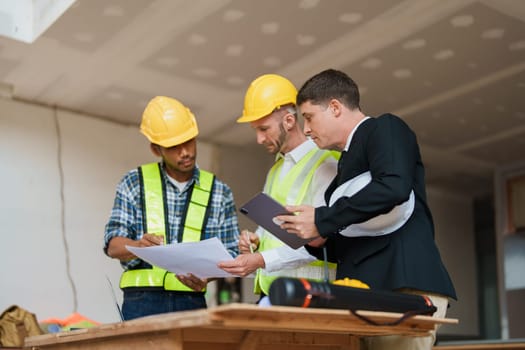 multi ethnic engineer brainstorming and measuring for cost estimating on paperworks and floor plan drawings about design architectural and engineering for houses and buildings.