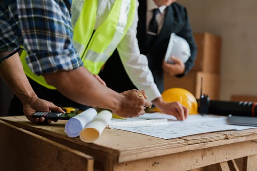 multi ethnic engineer brainstorming and measuring for cost estimating on paperworks and floor plan drawings about design architectural and engineering for houses and buildings.