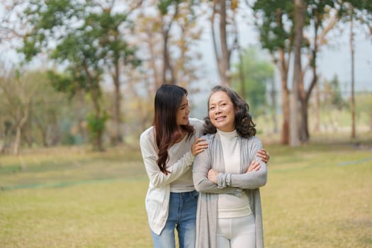 Grown daughter with aging mother showing love and walking together in the parkland.