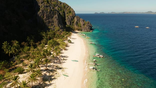 aerial view island with tropical sandy beach and palm trees. Malajon Island, Philippines, Palawan. tourist boats on coast tropical island. Summer and travel vacation concept. beach and blue clear sea water