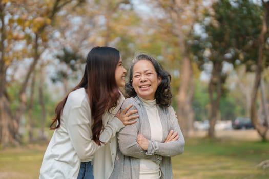 Grown daughter with aging mother showing love and walking together in the parkland.