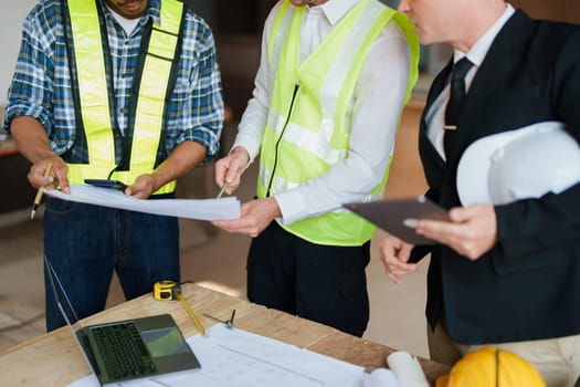 multi ethnic engineer brainstorming and measuring for cost estimating on paperworks and floor plan drawings about design architectural and engineering for houses and buildings.