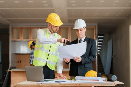 multi ethnic engineer brainstorming and measuring for cost estimating on blueprint and floor plan drawings about design architectural and engineering for houses and buildings.