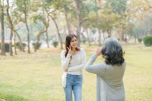 Asian teenage mother and daughter walking in park with camera to capture memories.