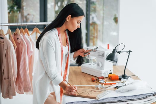 Working with precision. Seamstress is in her office that is with different clothes.