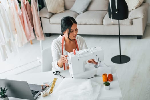 Professional sewing machine. Seamstress is in her office that is with different clothes.