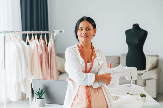 Standing and posing. Seamstress is in her office that is with different clothes.