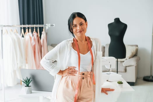 Standing and posing. Seamstress is in her office that is with different clothes.