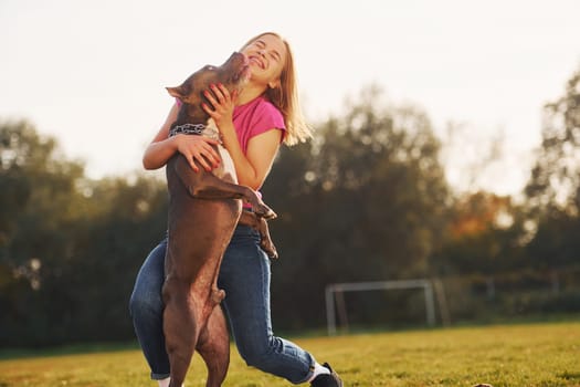 Friendship between human and animal. Woman in casual clothes is with pit bull outdoors.
