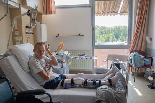 a man with a broken leg in an orthese in bed in a clinic after an accident, High quality photo