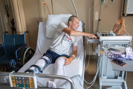 a man with a broken leg in an orthese in bed in a clinic after an accident, High quality photo