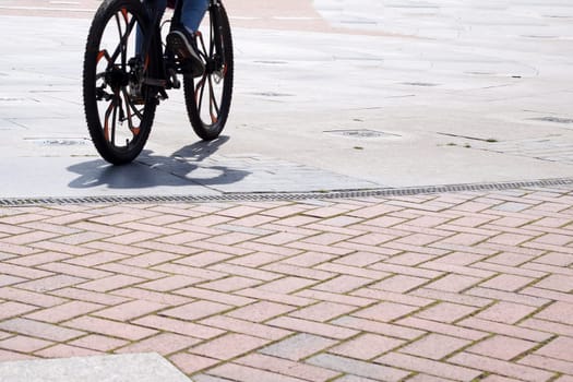 wheels of a riding bicycle with a shadow on the sidewalk, copy space