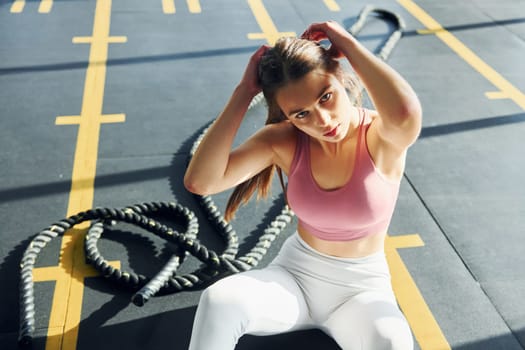 Sitting on the ground. Beautiful young woman with slim body type is in the gym.