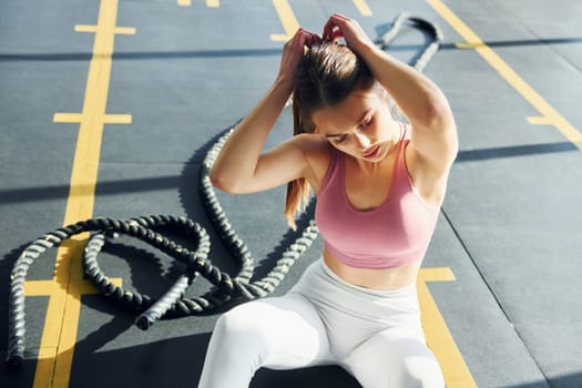 Sitting on the ground. Beautiful young woman with slim body type is in the gym.