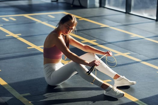 On the ground. Beautiful young woman with slim body type is in the gym.
