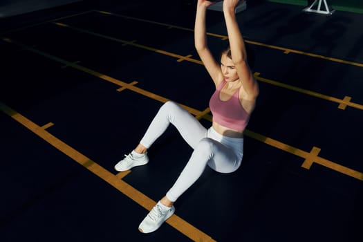 Holding weight in hands. Beautiful young woman with slim body type is in the gym.