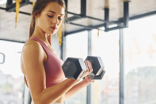 Focused on exercise. Beautiful young woman with slim body type is in the gym.