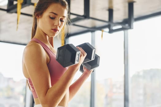 Focused on exercise. Beautiful young woman with slim body type is in the gym.