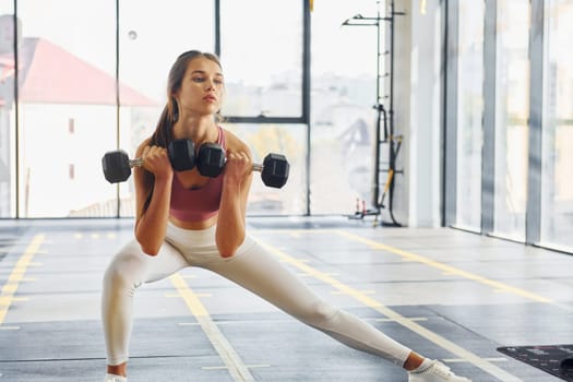 Focused on exercise. Beautiful young woman with slim body type is in the gym.