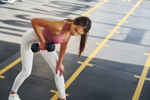 In white pants. Beautiful young woman with slim body type is in the gym.